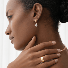 Woman wearing gold earrings and ring 